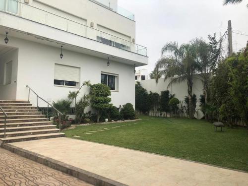 une maison blanche avec une cour en herbe à côté d'un bâtiment dans l'établissement Villa “el Jefe Del Mar”, à Casablanca