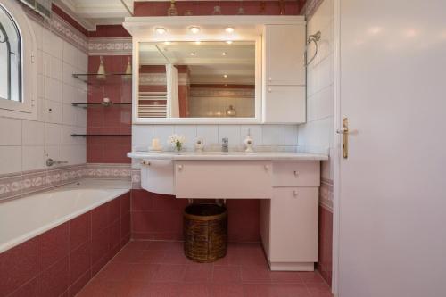een badkamer met een wastafel, een bad en een spiegel bij Villa Alkis in Sarakinádhon
