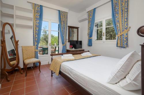 een slaapkamer met een bed, een tv en ramen bij Villa Alkis in Sarakinádhon