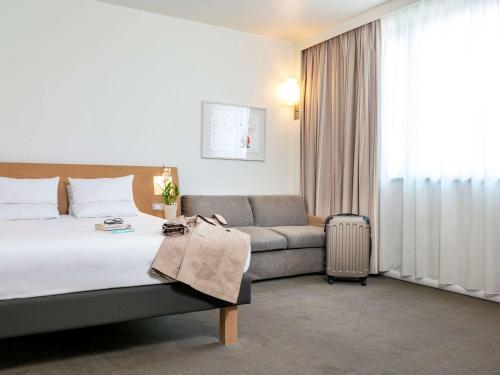 カルダーノ・アル・カンポにあるノボテル ミラノ マルペンサ エアロポルトのベッドとソファ付きのホテルルーム