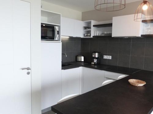 a kitchen with white cabinets and a black counter top at Appartement plage, piscine, balcon, animaux, parking - FR-1-194-201 in La Tranche-sur-Mer
