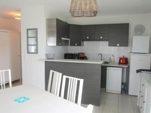 - une cuisine avec des armoires noires et un réfrigérateur blanc dans l'établissement Appartement Moderne à Capbreton Près des Plages avec Terrasse et Parking - FR-1-239-455, à Capbreton