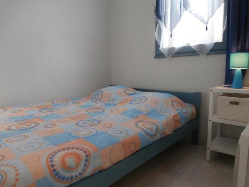 a small bedroom with a bed with a comforter and a window at Appartement Seignosse, 2 pièces, 4 personnes - FR-1-239-460 in Seignosse