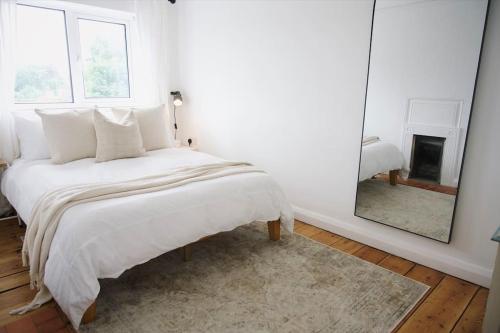 a white bedroom with a bed and a mirror at The Palm House Falmouth - minutes from the beach! in Falmouth