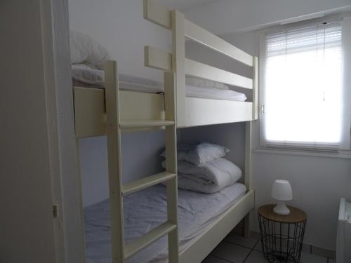 a bedroom with a bunk bed with pillows and a window at T2 Rénové avec Terrasse à 200m de la Plage, Proche Commerces - Les Sables-d'Olonne - FR-1-92-814 in Les Sables-dʼOlonne