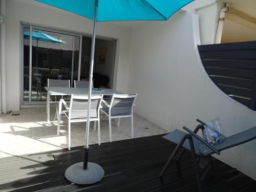 une table et des chaises avec un parasol sur une terrasse dans l'établissement T2 Rénové avec Terrasse à 200m de la Plage, Proche Commerces - Les Sables-d'Olonne - FR-1-92-814, à Les Sables-dʼOlonne