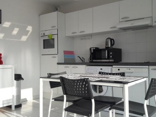 une cuisine blanche avec une table et des chaises dans l'établissement Proche plage avec parking et balcon à Fort-Mahon-Plage - FR-1-482-58, à Fort-Mahon-Plage