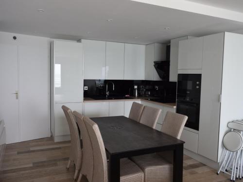 une cuisine avec des placards blancs et une table et des chaises noires dans l'établissement Appartement moderne 2 chambres, proche plage, jusqu'à 6 pers. - FR-1-197-423, à Les Sables-dʼOlonne