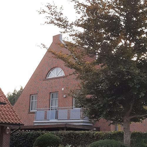 a red brick house with a window and a tree at Ferienwohnung Zweite Heimat 45248 in Ditzum