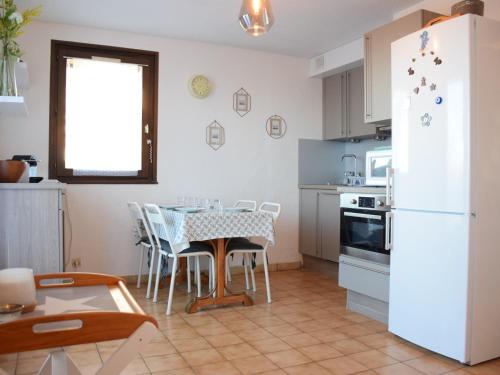 une cuisine avec une table et un réfrigérateur blanc dans l'établissement Appartement cosy au calme avec terrasse, parking, et internet à Évian - FR-1-498-15, à Évian-les-Bains