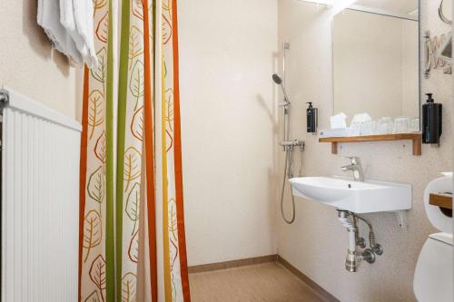 a bathroom with a shower curtain and a sink at Hotell Frykenstrand; Sure Hotel Collection by Best Western in Sunne