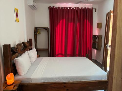 Lala salama Kendwa villas في كيندوا: غرفة نوم بسرير وستارة حمراء