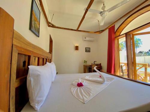 a bedroom with a white bed with a flower on it at Lala salama Kendwa villas in Kendwa