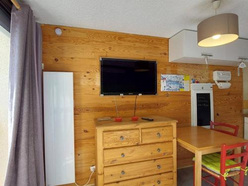 Cette chambre dispose d'un mur en bois, d'une télévision et d'une table. dans l'établissement Studio moderne au centre station avec balcon, idéal couple, proche commerces et pistes - FR-1-516-194, à Les Deux Alpes