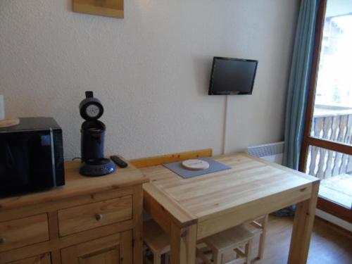 Cette chambre dispose d'une table en bois, d'une télévision et d'une table sidx sidx sidx. dans l'établissement Studio rénové pour 3 pers à Valfréjus, proche télécabine, parking gratuit - FR-1-561-106, à Modane