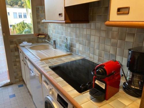 une cuisine avec un appareil rouge sur le comptoir dans l'établissement Bel appartement au Lavandou avec terrasse et vue mer - FR-1-308-167, au Lavandou