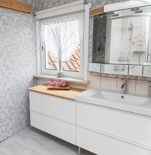 a white bathroom with a sink and a window at Ferienhaus "Am Staufenberg" in Blankenburg