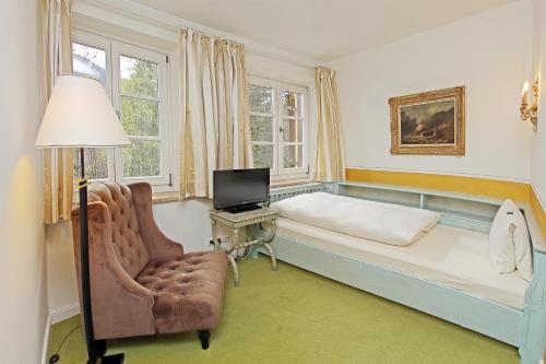 a bedroom with a bed and a chair and a television at Hotel Rex in Bad Wiessee