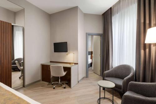 a hotel room with a desk and chairs and a television at Tbilisi Chambers, Trademark Collection by Wyndham in Tbilisi City