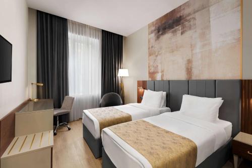 a hotel room with two beds and a desk at Tbilisi Chambers, Trademark Collection by Wyndham in Tbilisi City