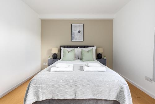 a white bedroom with a large bed with green pillows at The Camberwell Apartment in London