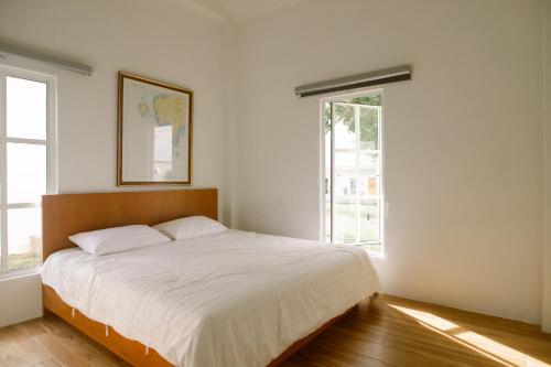 um quarto com uma grande cama branca e 2 janelas em Stayokay Sattahip -Airy House em Ban Tao Than
