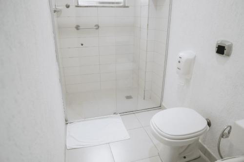 a white bathroom with a shower and a toilet at Pousada Areia do Forte in Cabo Frio