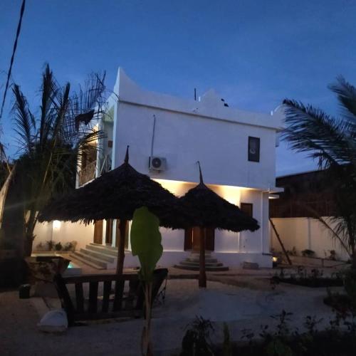 a white building with an umbrella in front of it at Lala salama Kendwa villas in Kendwa