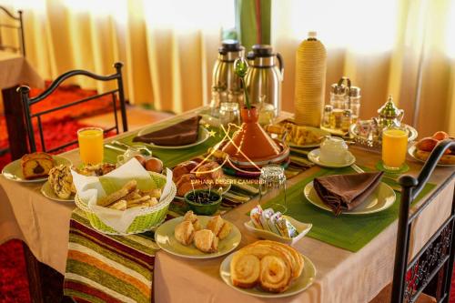 a table with plates of food on top of it at Sahara Desert Camping - Luxury Desert Camp Merzouga in Erfoud