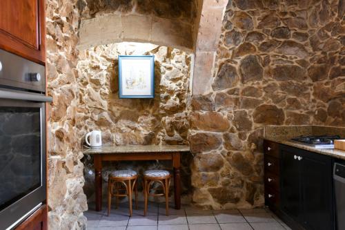 a stone walled kitchen with a table and stools at Ta'Filomena in Xagħra