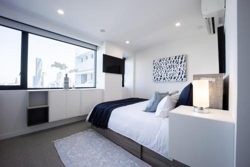 a white bedroom with a bed and a large window at Spring Hill - beautiful apartment in Brisbane