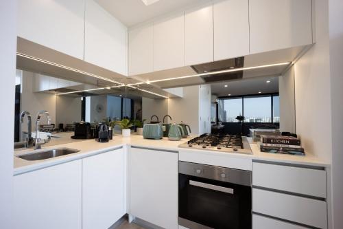cocina con armarios blancos y fogones en Spring Hill - beautiful apartment en Brisbane