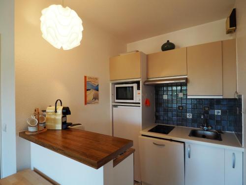 a kitchen with white cabinets and a wooden counter top at Appartement Arcachon, 2 pièces, 4 personnes - FR-1-474-32 in Arcachon