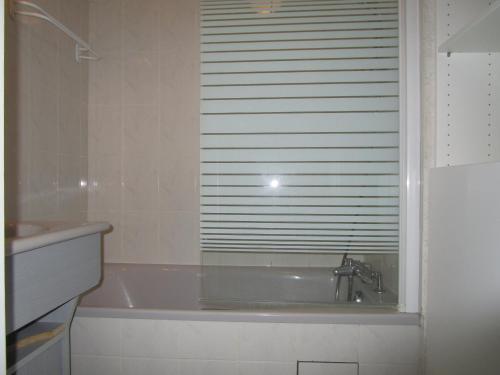 La salle de bains est pourvue d'une baignoire et d'une fenêtre avec un lavabo. dans l'établissement Appartement moderne avec terrasse à 100m de la plage des Sables-d'Olonne - FR-1-197-405, à Les Sables-dʼOlonne