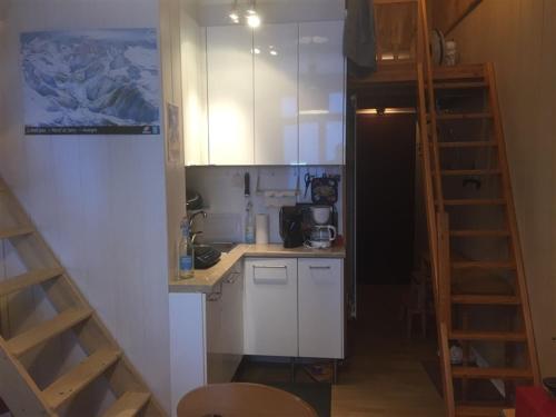 une petite cuisine avec des placards blancs et un escalier dans l'établissement F3 avec balcon, 2 chambres mezzanine, wifi, animaux acceptés, Mont-Dore - FR-1-415-71, à Le Mont-Dore
