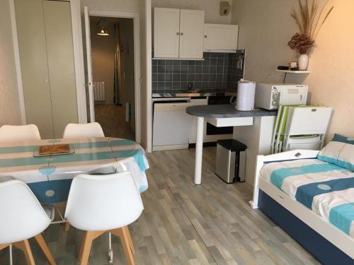 Cette petite chambre dispose d'une cuisine, d'une table et de chaises. dans l'établissement Fort-Mahon-Plage: Studio balcon, équipements complets, parking privé - FR-1-482-12, à Fort-Mahon-Plage