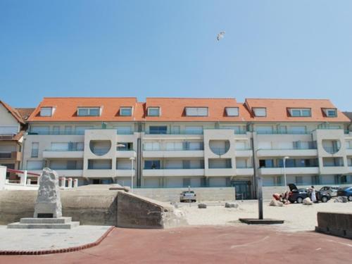 un grand immeuble d'appartements avec des personnes assises devant lui dans l'établissement Appartement T2 face mer avec balcon et animaux admis - FR-1-482-16, à Fort-Mahon-Plage