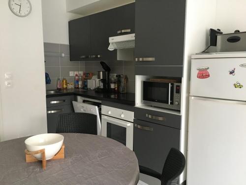 eine Küche mit einem Tisch und einem weißen Kühlschrank in der Unterkunft Charmante maisonnette à Fort-Mahon-Plage, près de la Baie d'Authie, 2 chambres, jardin, parking inclus - FR-1-482-38 in Fort-Mahon-Plage