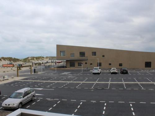 un parking avec des voitures garées devant un bâtiment dans l'établissement Charmant T2 à Fort-Mahon-Plage, à deux pas de la plage et du club de voile, parking inclus - FR-1-482-2, à Fort-Mahon-Plage