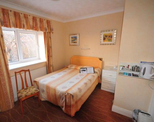 a small bedroom with a bed and a refrigerator at Devoncourt Monthly Rentals in Exmouth