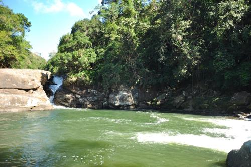 a river with a waterfall in the middle of a mountain at Pousada Encontro dos Rios in Lumiar