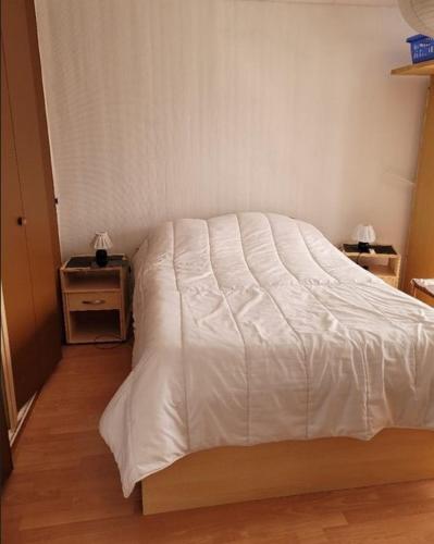 a white bed in a room with two night stands at Appartement f2 in Saint-Quentin
