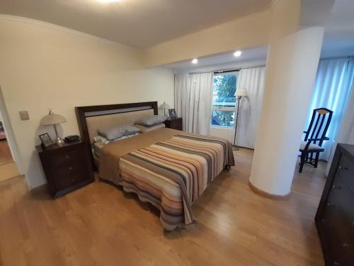 Un dormitorio con una cama con una manta a rayas. en Hermoso piso de categoría frente a plaza Mitre en Mar del Plata