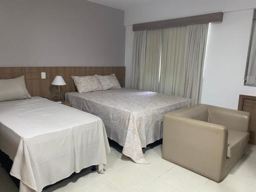 um quarto de hotel com duas camas e uma cadeira em Flat hotel saint moritz em Brasília