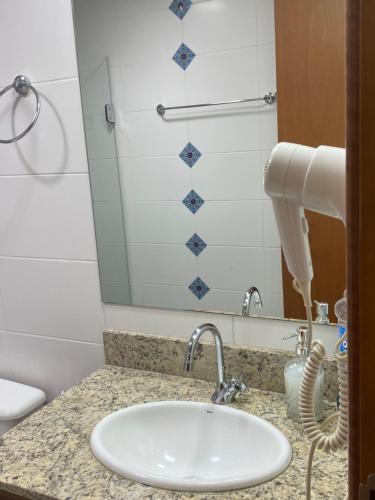 um balcão de casa de banho com um lavatório e um espelho em Flat hotel saint moritz em Brasília