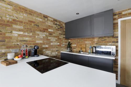 a kitchen with a brick wall and a counter top at Superfast WiFi studio, bathroom & own entrance in Brighton & Hove