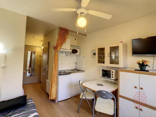 une petite cuisine avec une table et des chaises dans une pièce dans l'établissement Studio RDC proche centre et thermes avec Wifi - FR-1-451-76, à Lamalou-les-Bains