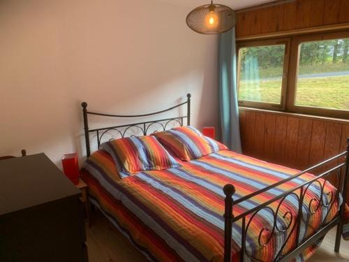 - un lit avec une couette colorée à rayures dans une chambre dans l'établissement Appartement Mont-Dore, 2 pièces, 4 personnes - FR-1-415-64, à Le Mont-Dore