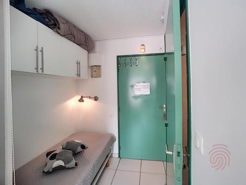 Cette petite chambre comprend un lit et une porte verte. dans l'établissement Studio rénové avec balcon, animaux acceptés, wifi, à 650m des Thermes - FR-1-451-92, à Lamalou-les-Bains