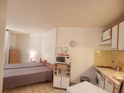 - une petite cuisine avec un lit et un four micro-ondes dans l'établissement Charmant appartement avec terrasse, parking gratuit et animaux acceptés, proche des thermes à Lamalou - FR-1-451-89, à Lamalou-les-Bains